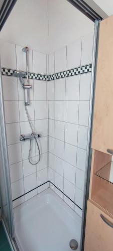 a shower in a bathroom with white tiles at Gästehaus Moorbad Gmös in Laakirchen