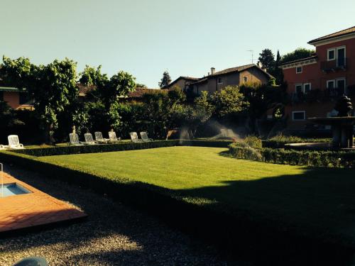 a lawn with chairs and a fountain in a yard at Hotel Vela D'oro ***S in Bardolino