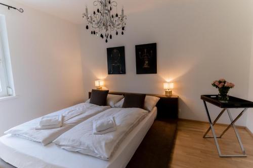 a bedroom with a bed with white sheets and a chandelier at Apartment Bungalow Sekirn in Sekirn