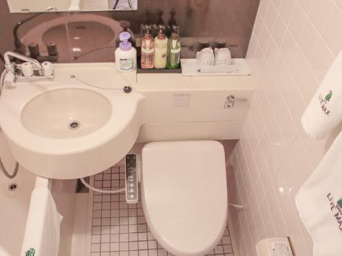 ein Badezimmer mit einem weißen WC und einem Waschbecken in der Unterkunft HOTEL LiVEMAX Kyoto Ekimae in Kyoto