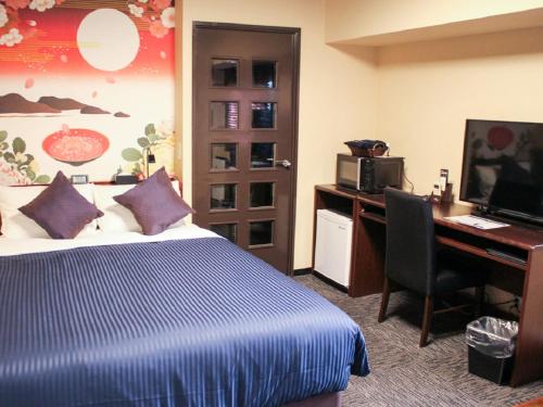 ein Hotelzimmer mit einem Bett, einem Schreibtisch und einem Computer in der Unterkunft HOTEL LiVEMAX Kyoto Ekimae in Kyoto