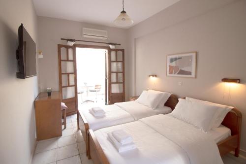 a hotel room with two beds and a window at Pomelo Rooms in Parga