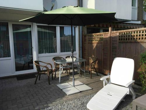 a patio with a table and chairs and an umbrella at Ferienwohnung Buhne 33 in Hooksiel