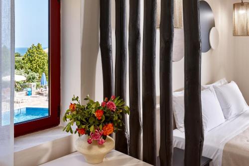 a vase with flowers on a table in a bedroom at Marni Village in Hersonissos