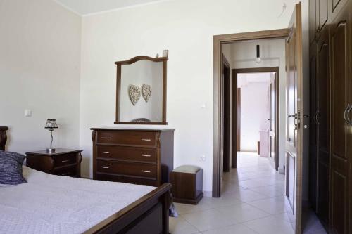 - une chambre avec un lit, une commode et un miroir dans l'établissement Villa Stelianna, à Engares