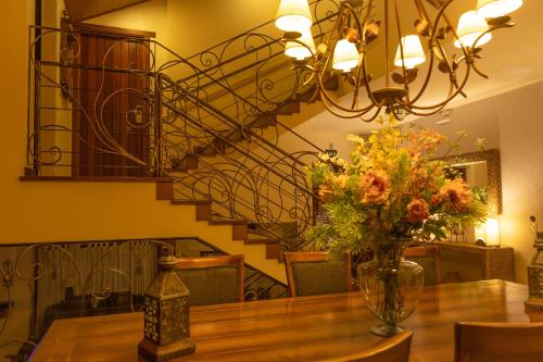 a vase of flowers on a table with a staircase at Casablanca Hotel Boutique in Campos do Jordão