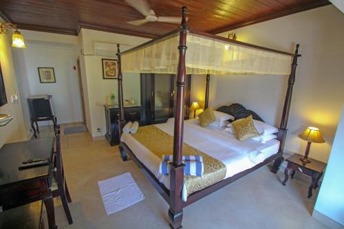 een slaapkamer met een hemelbed en een bureau bij Resort Coqueiral in Candolim