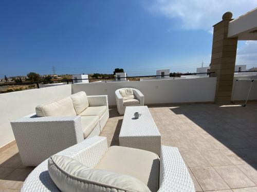 a patio with couches and tables on a roof at Pyla Palms A1 204 in Pyla