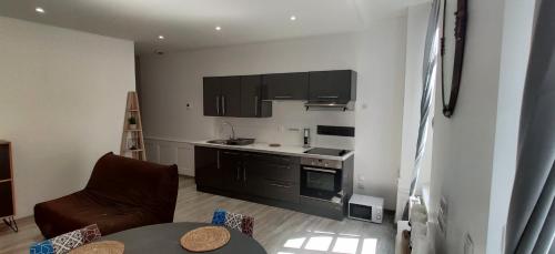 a kitchen with black cabinets and a table in a room at Appartement F2 dans le centre historique in Le Puy en Velay