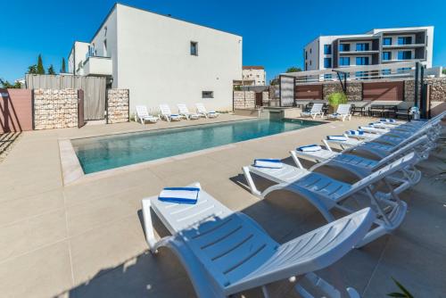 a row of lounge chairs next to a swimming pool at PINNA RESIDENCE - VANGA in Pula