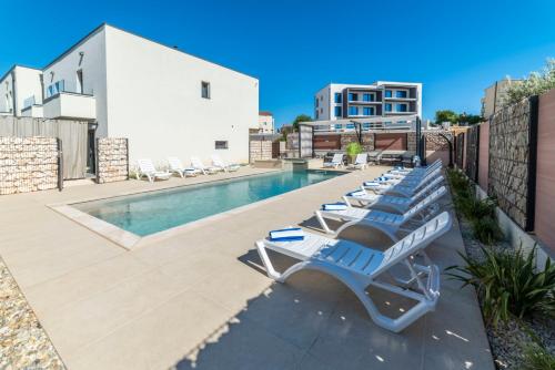a row of lounge chairs next to a swimming pool at PINNA RESIDENCE - VANGA in Pula