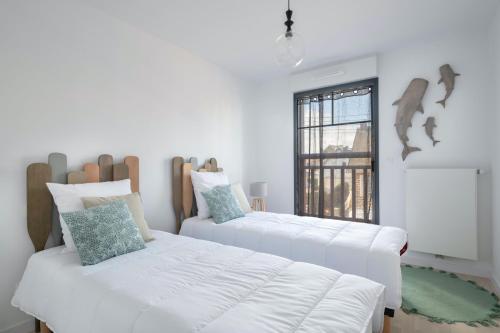 - 2 lits blancs dans une chambre avec fenêtre dans l'établissement À 50m de la plage, appartement vue mer 6 pers, à Pléneuf-Val-André