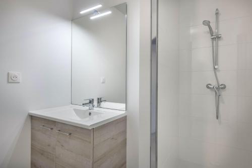 une salle de bain avec un lavabo et une douche avec un miroir dans l'établissement À 50m de la plage, appartement vue mer 6 pers, à Pléneuf-Val-André