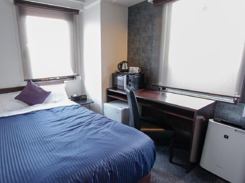 a bedroom with a desk and a bed with a blue comforter at HOTEL LiVEMAX Kobe Sannomiya in Kobe
