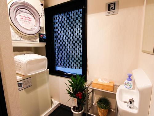 a bathroom with a sink and a tv in a room at HOTEL LiVEMAX Kobe Sannomiya in Kobe