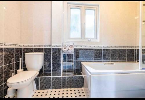 a bathroom with a toilet and a tub and a sink at Fantastic spacious house with beautiful panoramic views of the bay Only a few minutes walk from beach harbour and restaurants This house has 3 bedrooms 3 bathrooms and 2 lovely sitting rooms in Lyme Regis