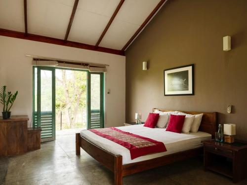a bedroom with a large bed with red pillows at Hide Yala in Tissamaharama