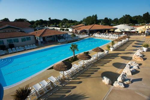 an overhead view of a swimming pool with chairs and umbrellas at MOBIL HOME - 6 Pers - LES CHARMETTES **** in Les Mathes