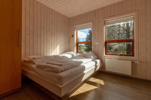 a bed in a room with two windows at Gorgeous Riverside Lodge in the South of Iceland in Reykholt