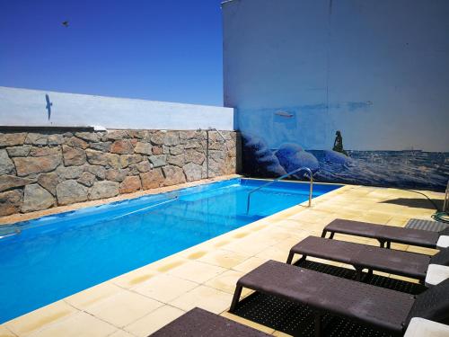 una piscina con dos bancos frente a ella en La Casona del Abuelo Parra, en Villanueva de los Infantes