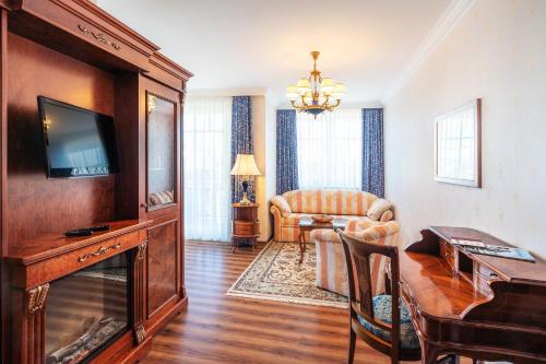 a living room with a television and a couch at SEETELHOTEL Ahlbecker Hof das elegante Traditionshotel & ruhiger Rückzugsort an der Ostsee in Ahlbeck