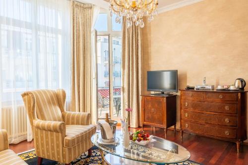 a living room with a television and a chair and a table at SEETELHOTEL Ahlbecker Hof das elegante Traditionshotel & ruhiger Rückzugsort an der Ostsee in Ahlbeck