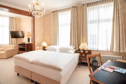 a bedroom with a large bed and a chandelier at SEETELHOTEL Ahlbecker Hof das elegante Traditionshotel & ruhiger Rückzugsort an der Ostsee in Ahlbeck