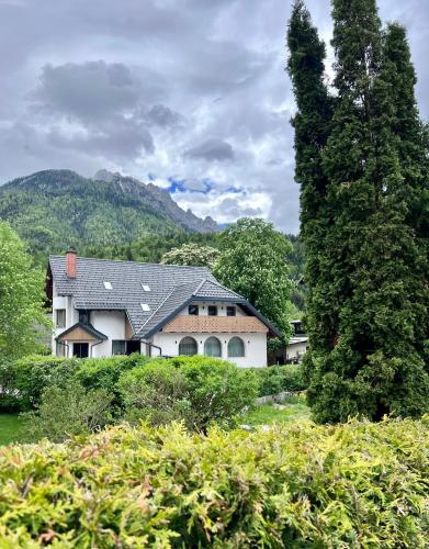 a large white house with mountains in the background at Apartments and Rooms Kaja in Kranjska Gora