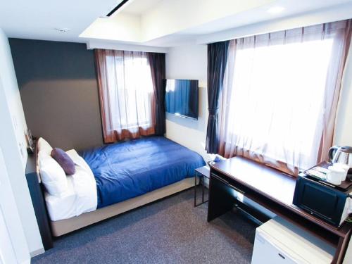 a bedroom with a bed and a tv and windows at HOTEL LiVEMAX Shinsaibashi East in Osaka
