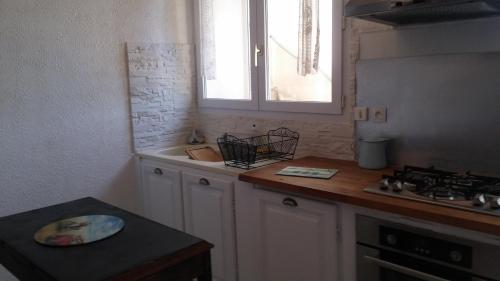 a kitchen with white cabinets and a sink and a window at GITE PAPY ALBERT in Gruissan