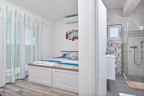 a small bedroom with a bed and a shower at Apartments & Rooms Seaside in Kaštela