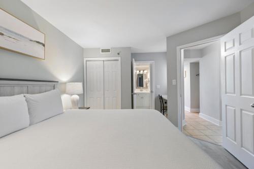 Un dormitorio con una cama blanca y un pasillo. en Scenic Views from the balcony at Ocean Forest Plaza Condos, en Myrtle Beach