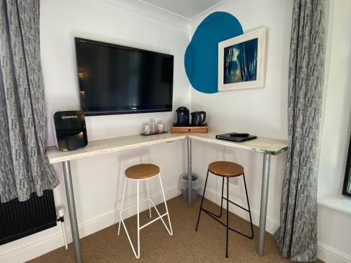 een kamer met een bureau, een tv en 2 krukken bij Copperbeech B&B in Yoxford