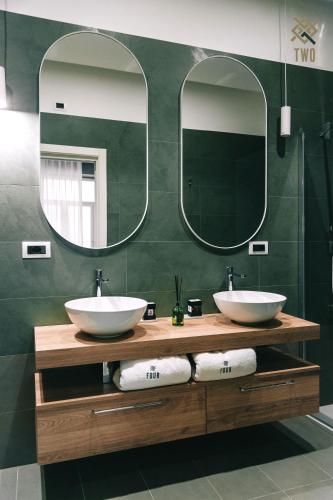 two sinks in a bathroom with two mirrors at Four Pompei in Pompei