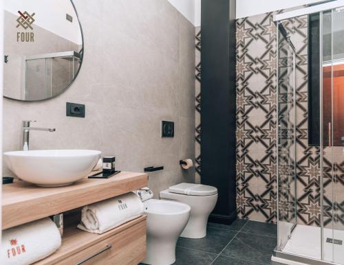 a bathroom with a sink and a toilet and a mirror at Four Pompei in Pompei