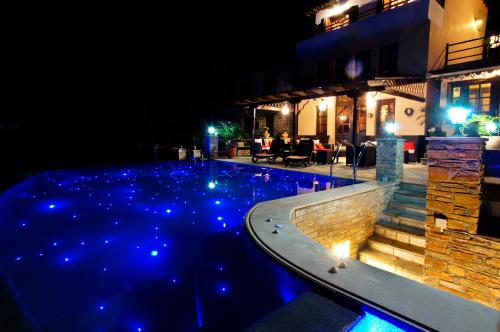 una piscina por la noche con luces azules en Hotel Dryalos, en Milies