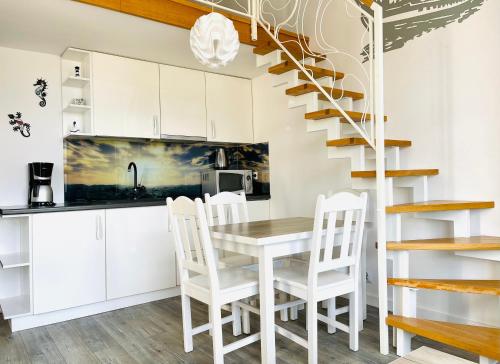 a kitchen with a table and chairs and a spiral staircase at Chrobry by Baltic Home in Międzyzdroje