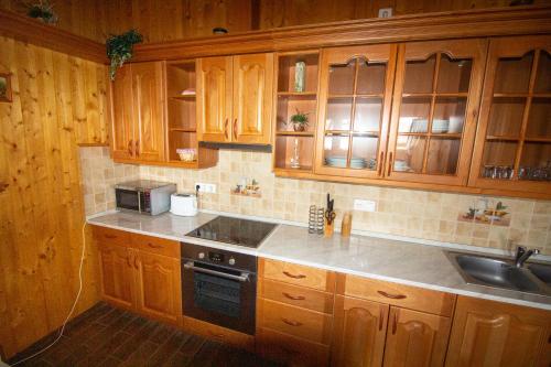 a kitchen with wooden cabinets and a sink and a stove at Radics Panzió Étterem és Pihenő Központ in Letenye