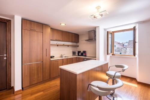 een keuken met houten kasten en een witte stoel bij Peristil Apartment in Split