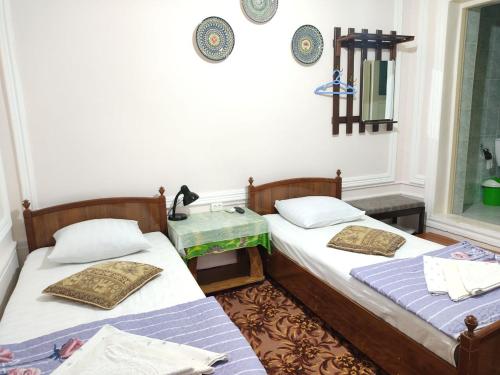 two beds sitting next to each other in a room at Hotel Nazira & Azizbek in Bukhara
