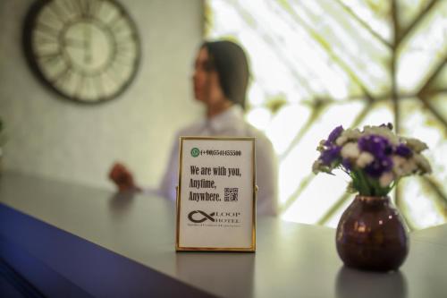 a sign sitting on a counter with a vase of flowers at Loop Hotel Bosphorus İstanbul in Istanbul