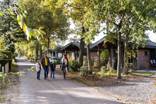 a family walking down a sidewalk in front of a house at Europarcs De Wije Werelt in Otterlo