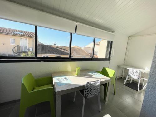 Zimmer mit einem Tisch, Stühlen und einem Fenster in der Unterkunft Bel appartement à 300 mètres de la plage +parking in Valras-Plage