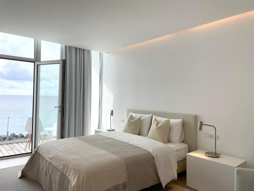 サン・ロケにあるBarrocas Villas Azoresの白いベッドルーム(ベッド1台、大きな窓付)