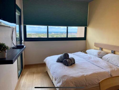 a bedroom with a bed with a large window at קיסריה נאות גולף- Oren Apartment in Caesarea