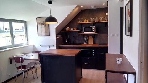 une cuisine avec un comptoir, une table et un four micro-ondes dans l'établissement Les Appartements du 31 - Centre Ville - 3è étage - 35m2, à Quimper