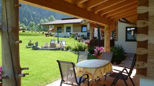 a patio with a table and chairs and a house at Almdorf Tirol in Haldensee