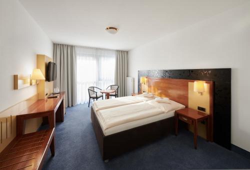 ein Hotelzimmer mit einem großen Bett und einem Schreibtisch in der Unterkunft Stadthotel am Wasen in Stuttgart