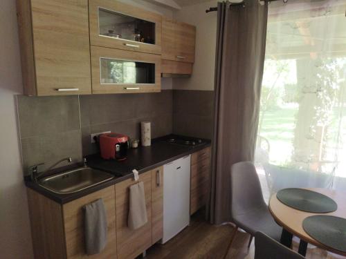 uma pequena cozinha com um lavatório e uma mesa em Daniel Apartman em Tahitótfalu
