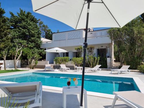une villa avec une piscine et un parasol dans l'établissement Villa FLAMINGO Deluxe Novalja, à Novalja